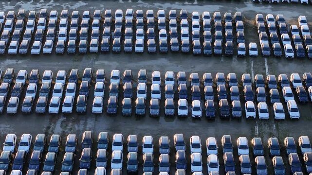 Drone view shows imported cars parked in parallel rows inside a logistics storage yard, highlighting large scale vehicle handling, industrial organization, transport infrastructure,