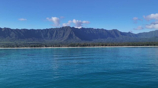 4k drone video far out from waimanalo beach in oahu hawaii showing deep blue ocean and koolau mountains in distance and white sand beach