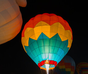 colorful hot air balloons glowing against dark night sky