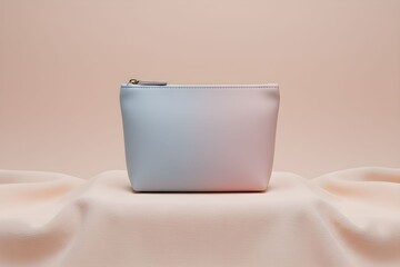A pale blue cosmetic bag on a soft, draped fabric against a light background