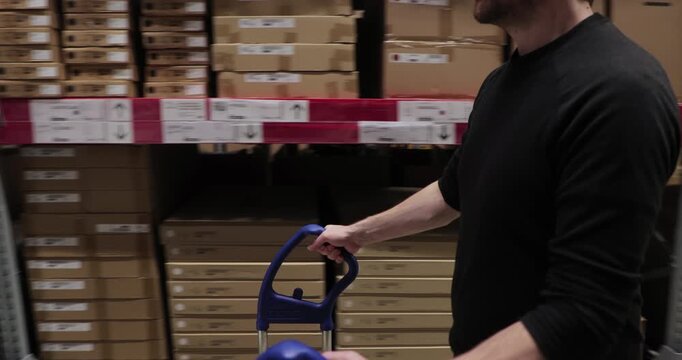 Warehouse with stocked shelves of boxes, man with cart