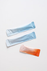 Two light blue and one orange stick packet showing single dose packaging.