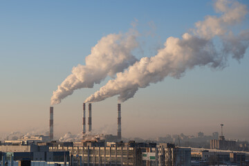 Smoke from factory pipe of heat station in the city in winter time at frosty weather in Europe....