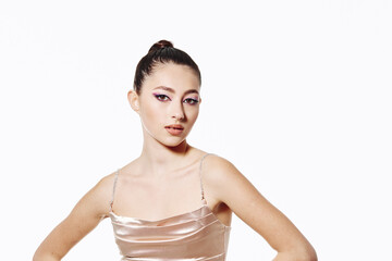 Fashionable young woman with sleek bun and shimmering makeup wearing a light champagne slip dress...