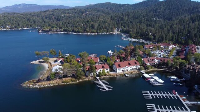 Village of Lake Arrowhead, California, USA. Calm water showing lush green forest, mountain lake, and the village town with shops in the San Bernardino Mountains along the route to Big Bear.
