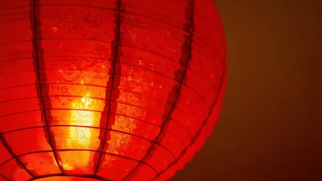 Red paper lantern glowing warm light with textured patterned glow festive ambiance and soft shadow