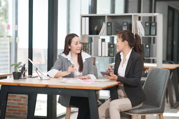 Obraz premium Asian businesswoman sitting at work using laptop talking and consulting in office 