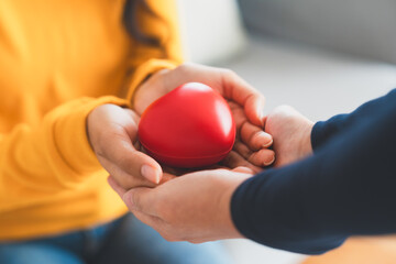 Closeup view of red heart on woman and man hands. Healthy and valentines day concept