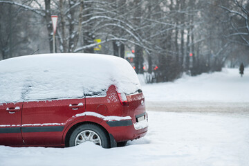 Side view of snow covered car. Red car parked in a winter parking lot during a chilly season © Dmitriy