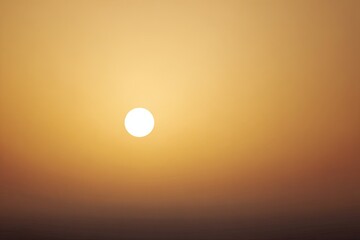 Sunrise or sunset, featuring a golden-hued sky with a bright, round sun