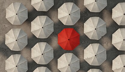 Overhead shot of a red umbrella amidst several closed white umbrellas on a concrete surface