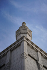 Obraz premium Geometric Minaret Majesty: Low-Angle View of Islamic Lattice Tower Against Blue Sky