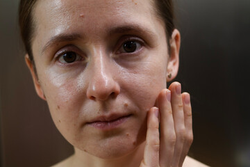 Fototapeta premium Natural portrait of a young woman with clean skin and minimal makeup, showing real facial texture and calm emotion. Authentic lifestyle beauty concept, skincare, self care, natural appearance
