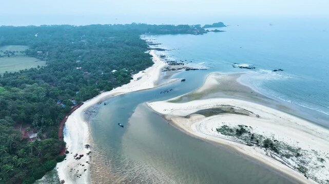 Scenic aerial drone shot of Konkan coast, river merging into ocean, tropical trees along the beach, calm sea waves, golden sunlight, tranquil tropical landscape, natural beauty, serene environment, we