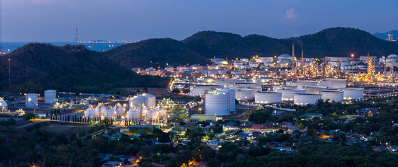 Panoramic night view of a large oil refinery and petrochemical plant located near mountains. Industrial energy estate landscape with illuminated storage tanks and distillation towers at twilight. © Yellow Boat