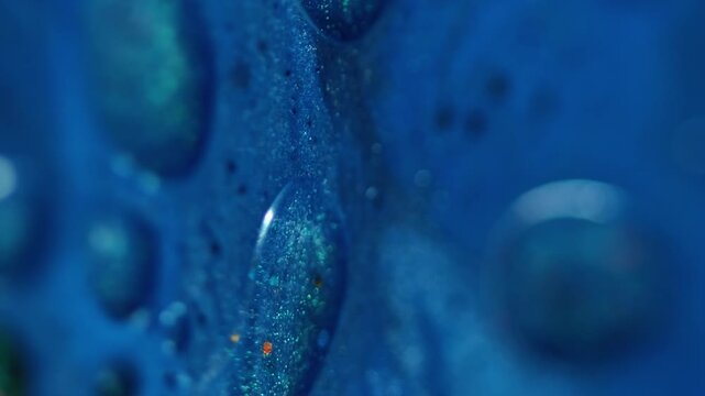 Vertical video. Shiny oil. Blend flow. Defocused blue colorful ink water marble sparks chemical texture enamel fluid moving on abstract background.
