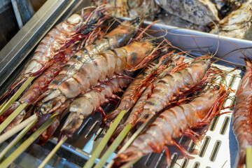Large king prawns on bamboo skewers at a popular Asian market. Traditional Japanese street food.