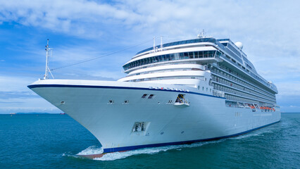 Naklejka premium a majestic white luxury cruise ship sailing in the blue sea under a cloudy sky. Massive passenger vessel showing bow and cabin balconies. International tourism vacation concept.