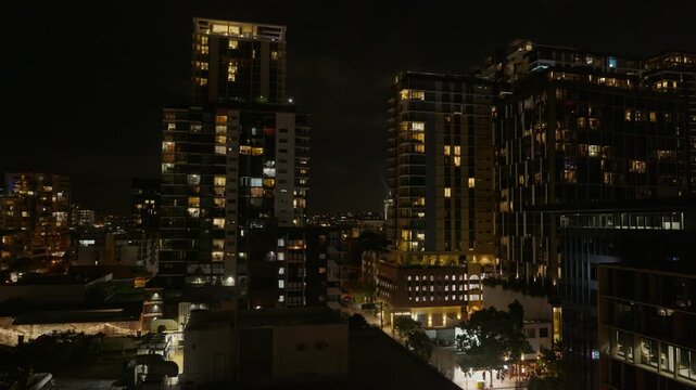 Brisbane City at night time with lights flickering and people walking in the street.