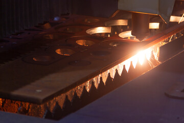 Cutting metal with a laser machine, the laser head cuts the metal, sparks fly when it comes into contact with the surface