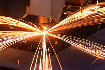 Cutting metal with a laser machine, the laser head cuts the metal, sparks fly when it comes into contact with the surface