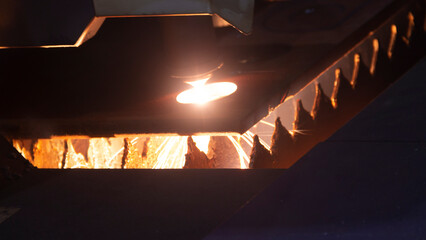 Cutting metal with a laser machine, the laser head cuts the metal, sparks fly when it comes into...