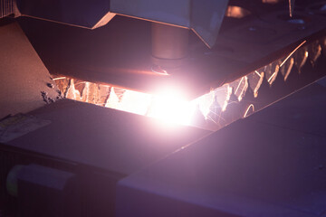 Cutting metal with a laser machine, the laser head cuts the metal, sparks fly when it comes into...