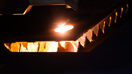 Cutting metal with a laser machine, the laser head cuts the metal, sparks fly when it comes into contact with the surface