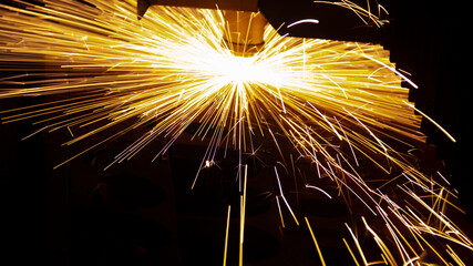 Cutting metal with a laser machine, the laser head cuts the metal, sparks fly when it comes into contact with the surface