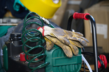 Work gloves resting on an air compressor with a coiled hose and yellow safety helmet