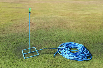 Garden hoses and sprinkler heads stans by on the lawn.