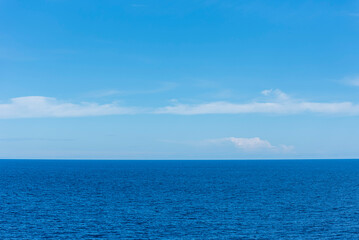 Obraz premium Calm blue ocean with a clear horizon line under a bright blue sky, creating a peaceful seascape background.