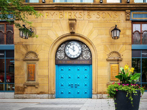 Henry Birks and Sons Limited building facade centers ornate clock above turquoise studded doors, carved sandstone masonry, engraved plaques - Montreal, Canada - July 1, 2025