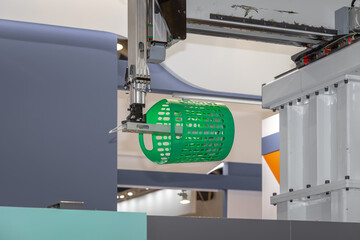 Automated process of molding plastic products on a CNC machine. The robotic arm of the machine moves the newly made green plastic basket. Injection molding of plastic objects