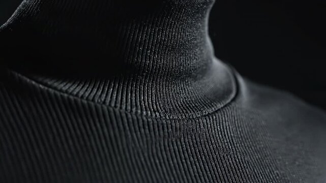 Timeless Turtleneck: A close-up view of a classic black turtleneck, its ribbed texture and elegant neckline highlighted against a dark backdrop. The image speaks of timeless fashion and simplicity.