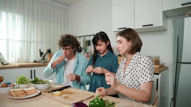 Happy caucasian father and mother sitting and eating fruit at modern kitchen. Energetic family spend time together by enjoy eating fruit or healthy fruit with kitchenware and fruit on table. Pedagogy.