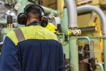 Marine engineers inspecting main engine in ship engine room.