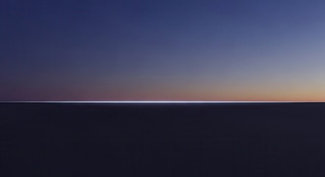Thin bright horizon line separates a dark foreground from a deep twilight sky above