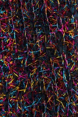 Black fabric interwoven with shiny vibrant strands of blue, gold and red. Great for a background.