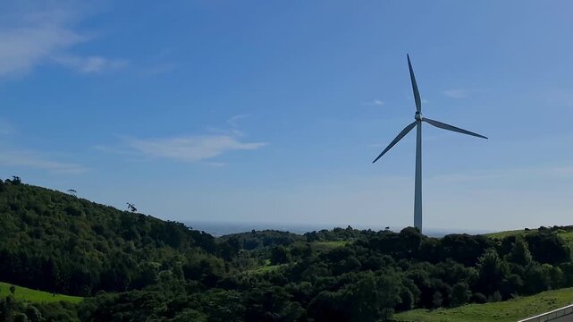 arge wind turbines on rolling green hills under a bright blue sky
