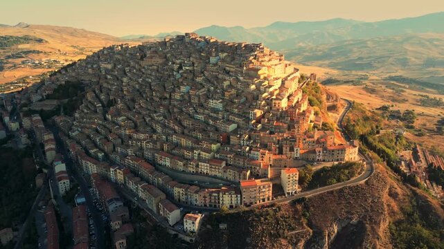 Cinematic drone view flying above Gangi, showcasing tightly packed stone houses cascading down the hillside.High-angle drone shot of Gangi village highlighting its unique circular urban layout and