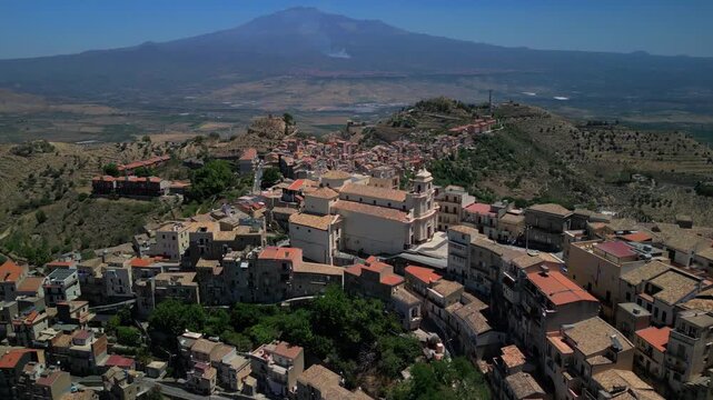High-altitude drone shot capturing Centuripe surrounded by rolling hills and the Etna massif in the distance. Drone footage showcasing Centuripe&rsquo;s distinctive layout glowing in warm evening light.