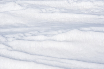 Textured white snow surface with gentle undulations and soft shadows, creating a serene winter...