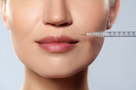 Woman receiving cosmetic treatment on the lips in a clinical setting with a syringe