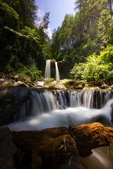 Obraz premium Serene Waterfall Cascading Down Rocky Terrain in Lush Forest