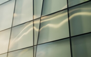 Modern architectural facade with geometric glass panels reflecting light and abstract patterns.