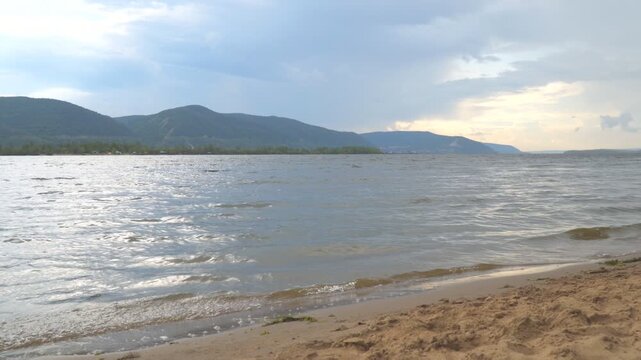 View of the Zhiguli mountains from the sandy shore in cloudy weather. The Volga River.
