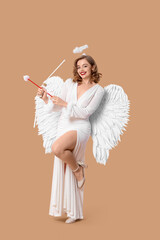 Young woman dressed as Cupid with bow on beige background Valentine's Day celebration