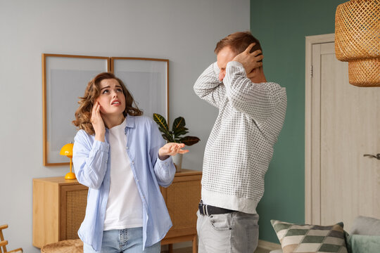 Young couple suffering from noisy neighbours at home
