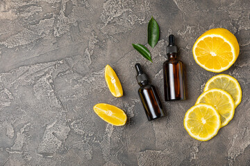 Lemon essential oil in a bottle with sliced ​​lemon and leaves on a wooden background. Lemon...